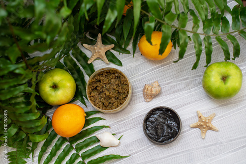 image of homemade cosmetics ingredients. aroma theme. Black mask, clay. organic cosmetics with extracts of herbs apples, lemons and oranges on white leaf green background