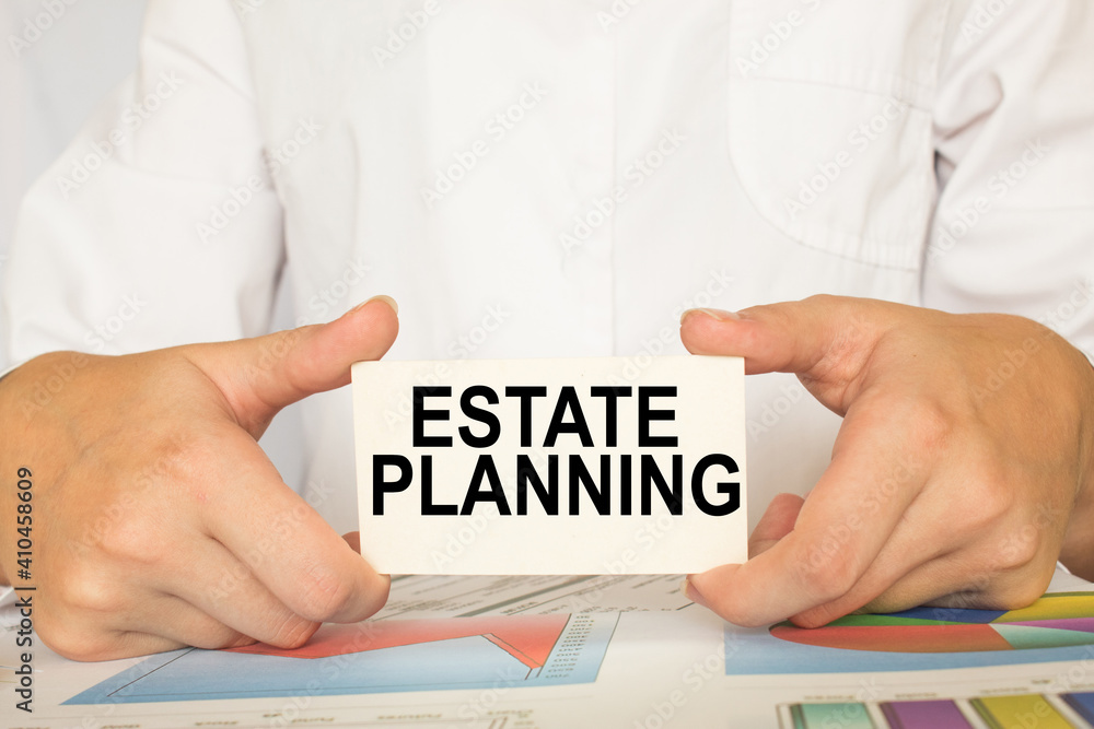 a man in the office holds a card with text ESTATE PLANNING . business concept a man in the office holds a card with text ESTATE PLANNING . business concept