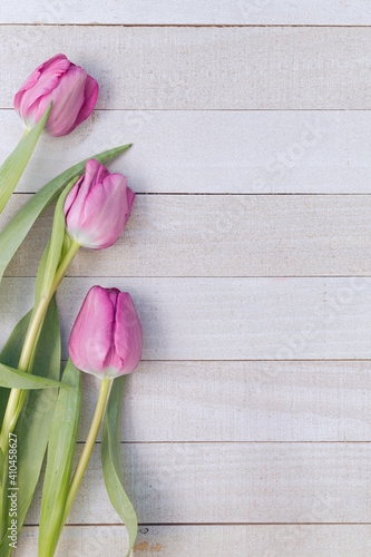 Ramo de tulipanes color rosa sobre una mesa de madera en color blanco.