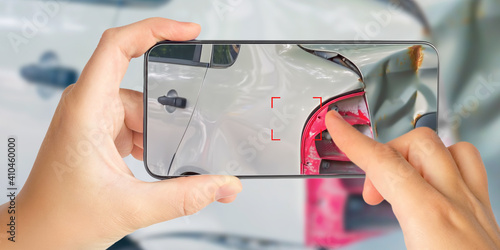 A girl takes pictures on a smartphone of car damage at the scene of an accident for insurance compensation. Selective focus.
