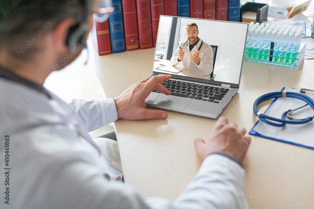 Doctor in front of a laptop monitor during an online video call. Conversation with a colleague.