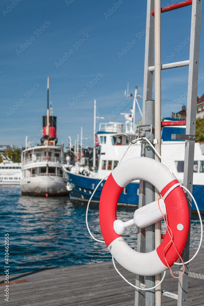 lifebelt on a pier with boats and ferries in the background