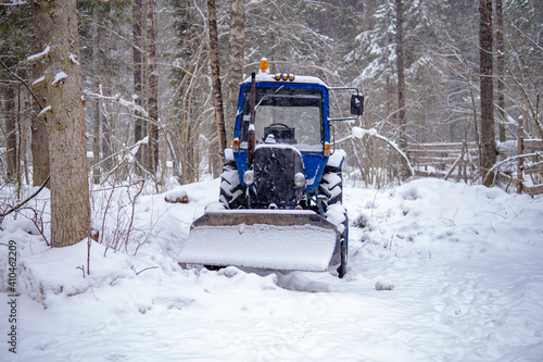  blue tractor skidded by snow, it stands in a forest strip