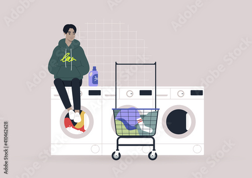 Household chores concept, a young male Asian character waiting for their laundry in a coin laundromat