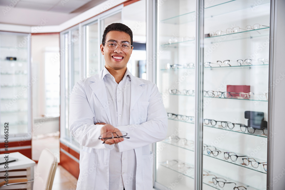 Smiling optometrist offering trendy glasses to customers Smiling optometrist offering trendy glasses to customers