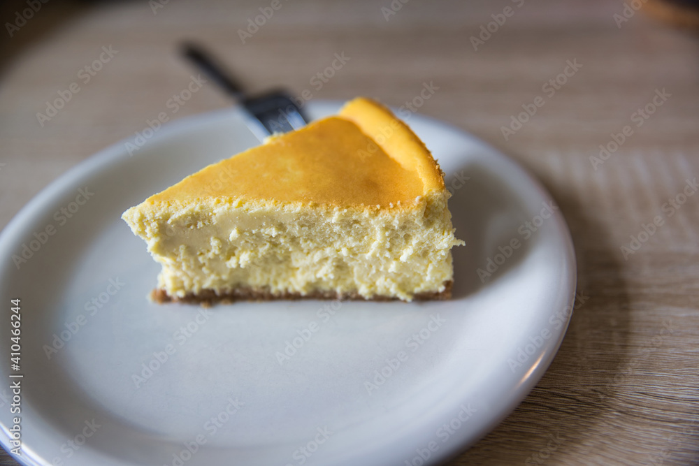Slice of new york cheesecake on a white plate with fork. Depth of field