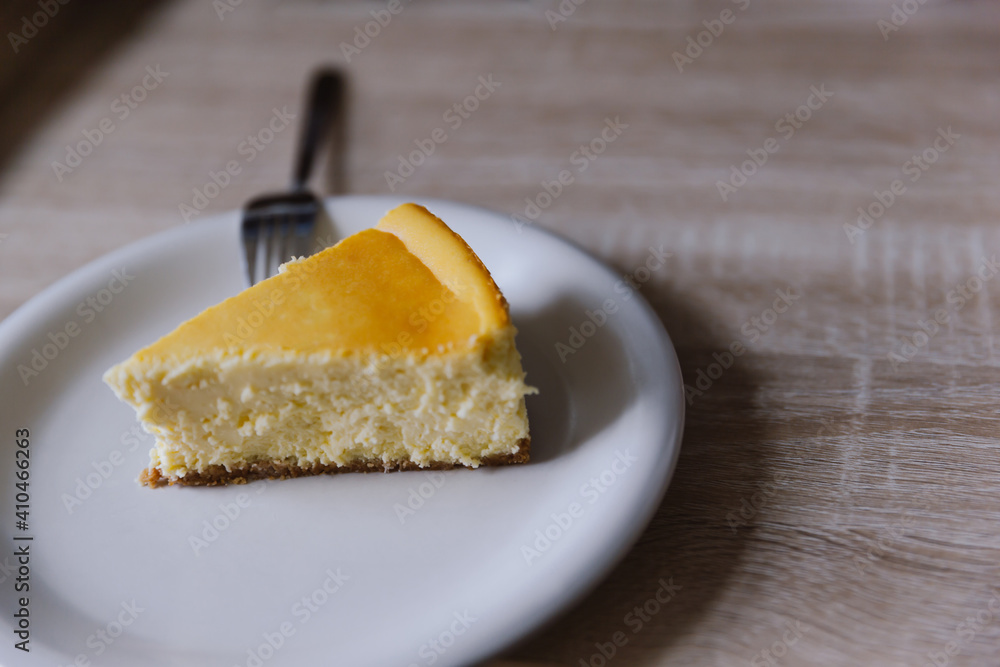 Slice of new york cheesecake on a white plate with fork. Depth of field