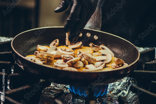 Chef at work. Hand holds a hot pan with fried vegetables  photo