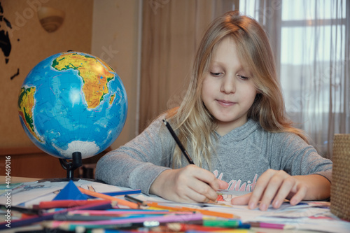 Little girl drawing on her book and having fun at playtable. Child girl does her school homework at home. photo