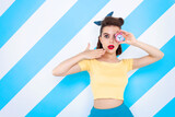 Sexy surprised woman with alarm clock in hands and open mouth. Colorful background in pop art retro comic style on striped blue background. Pinup and pop art concept