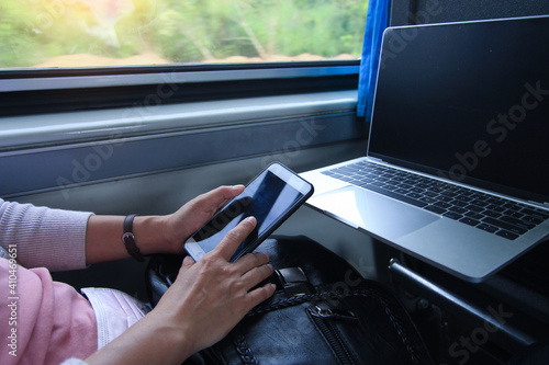 Woman playing cell phone while sitting on the train by the window