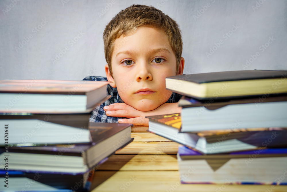 Portrait of a sad boy lying among children's books, standing on a wooden table. Portrait of a sad boy lying among children's books, standing on a wooden table.
