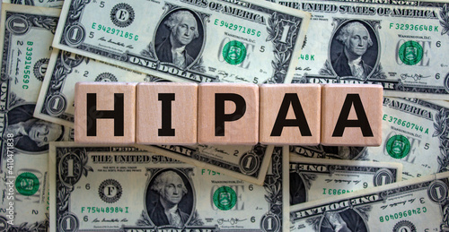 HIPAA, Health Insurance Portability and Accountability Act of 1996 symbol. Words 'HIPAA, Health Insurance Portability and Accountability Act', dollar bills background. Business concept. Copy space.