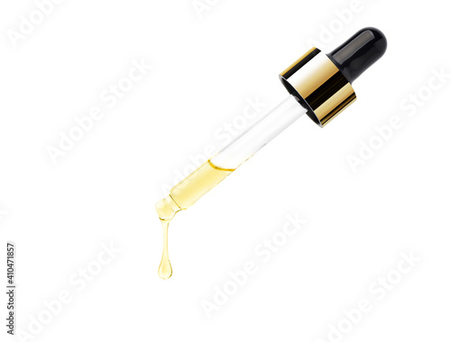 Yellow essential serum oil dripping from gold dropper  isolated on white background. Clipping path. photo