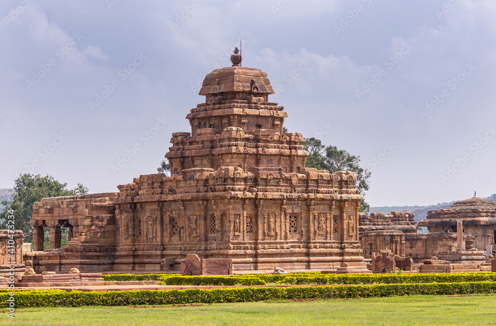 Bagalakote, Karnataka, India - November 7, 2013: Pattadakal temple complex. Brown stone Sangameshwara temple building with sanctum in front under blue cloudscape and set in green park.