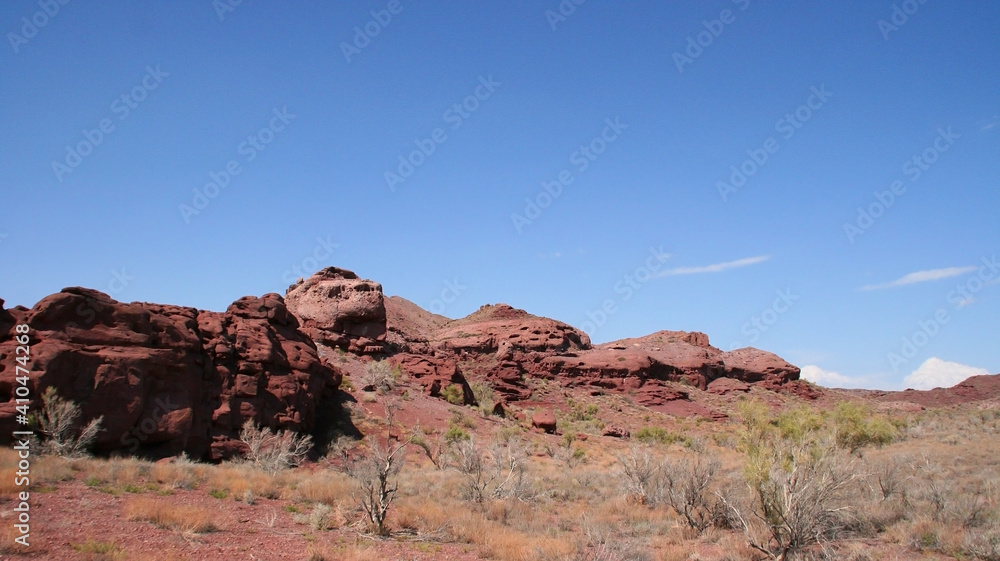 View of a Rock at Katutau red mountain range on a sunny blue sky day. Nature reserve Altyn Emel. Kazakhstan. Rock formations with interesting shapes. Frozen lava stones.