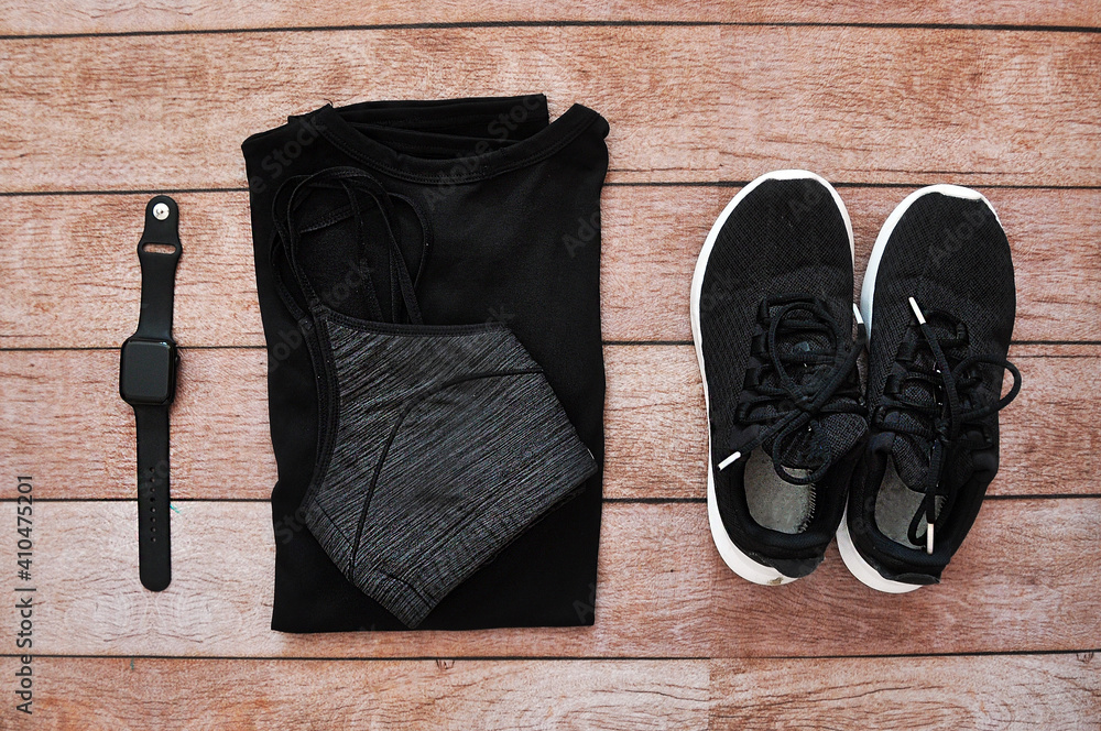 Woman's sport clothes: sport bra, t-shirt and a black smart watch. Everything on a wooden background. Woman's sport clothes: sport bra, t-shirt and a black smart watch. Everything on a wooden background.