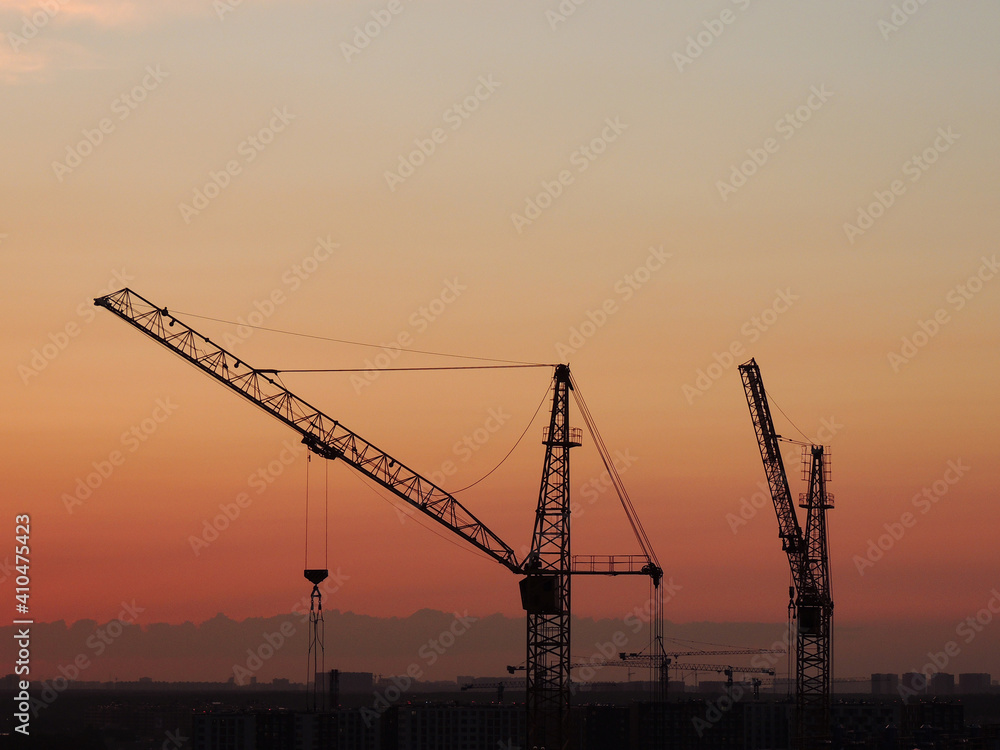 High construction cranes on the background of the sunset sky