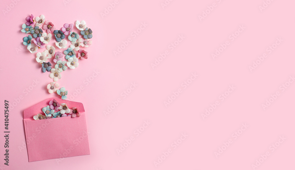 A heart shape of white, blue and pink flowers spills out of the envelope on a pink background. Valentine's Day, love, congratulations. Pastel colors. Top view, banner, space for text