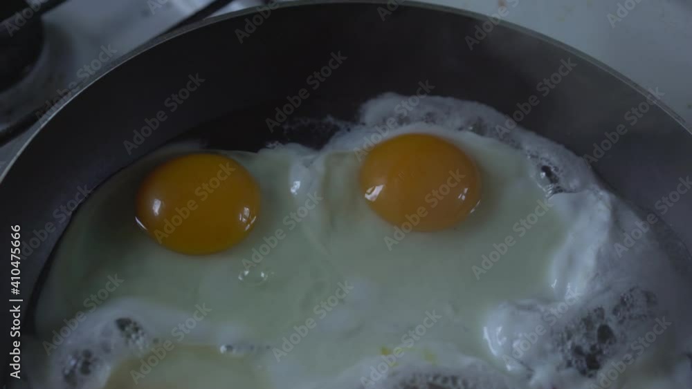 Fried eggs with two large yolks are fried in skillet for quick breakfast. Home cooking concept. Fried eggs with two large yolks are fried in skillet for quick breakfast. Home cooking concept.
