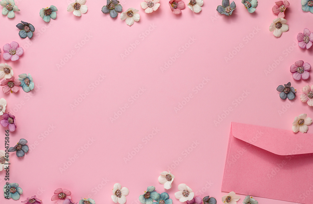 A clean pink envelope and pastel-colored flowers in the form of a frame on a pink background. Valentine's Day, Birthday, wedding, congratulation. Flat lay, copy space
