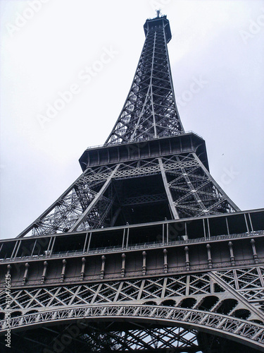 Paris. Eiffel Tower In Paris. Looking Up At The Famous Iron Tower In Paris, Against A Gray Cloudy Sky. Travels