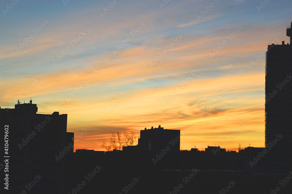 The dark silhouette of the city against the background of the dawn sky. Dawn sky with colorfull clouds. Sunrise landscape.
