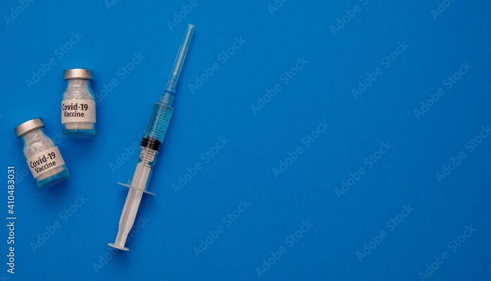 Vaccine for Covid 19 and a medical needle filled with vaccine on a blue background Vaccine for Covid 19 and a medical needle filled with vaccine on a blue background