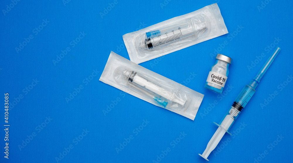 Obraz premium Coronavirus vaccine concept and syringe on blue background with copy space