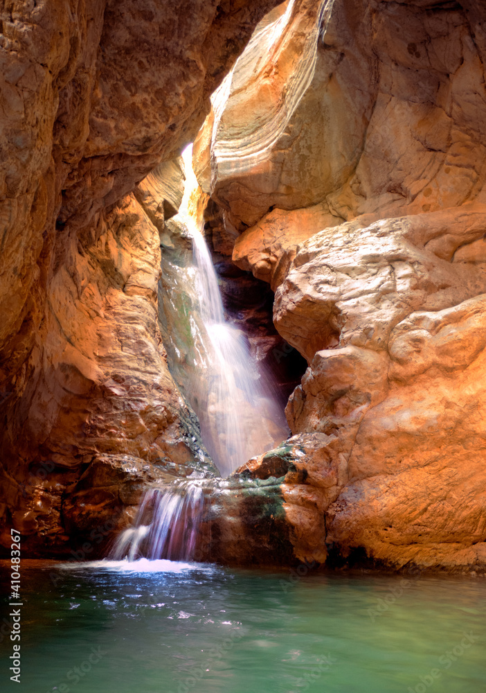 waterfall passing between rocks with light streaming overhead