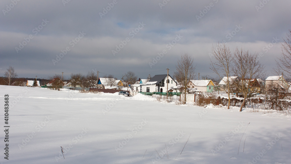 Suburbs of Grodno. Belarus. Winter landscape outside the city. Snow-covered field and small summer houses of the suburban village.