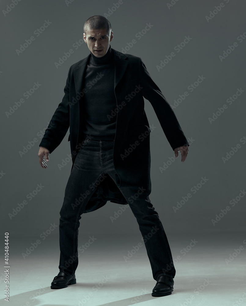 Handsome brave young man dressed in black stylish clothes stylish, detective or spy on gray studio background. Handsome brave young man dressed in black stylish clothes stylish, detective or spy on gray studio background.