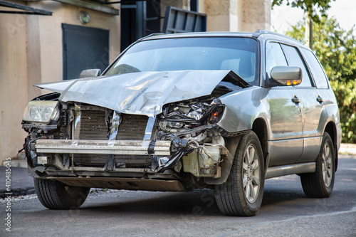 Crashed car in car accident. Broken vehicle after fatal disaster. Road collision damage. Gray car get damaged by accident. Damaged automobile after collision.