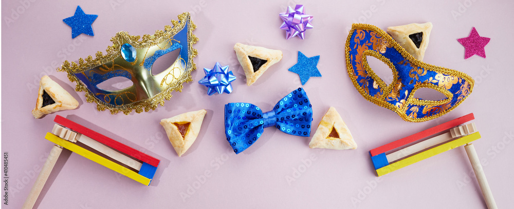 Fototapeta premium Purim celebration. Hamantashen or haman ears, noisemaker and mask on grey background. Top view