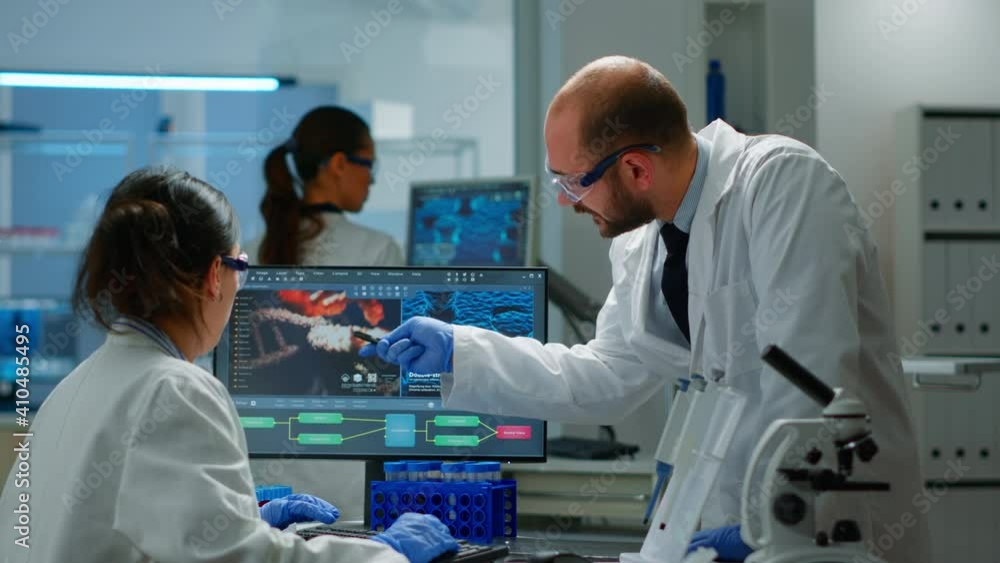 Team of scientists worried about virus evolution discussing in equipped laboratory pointing at computer. Stuff examining vaccine development using high tech researching treatment against covid19 virus
