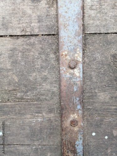 industrial background of gray old wooden plank surface with rusty iron strip with dots