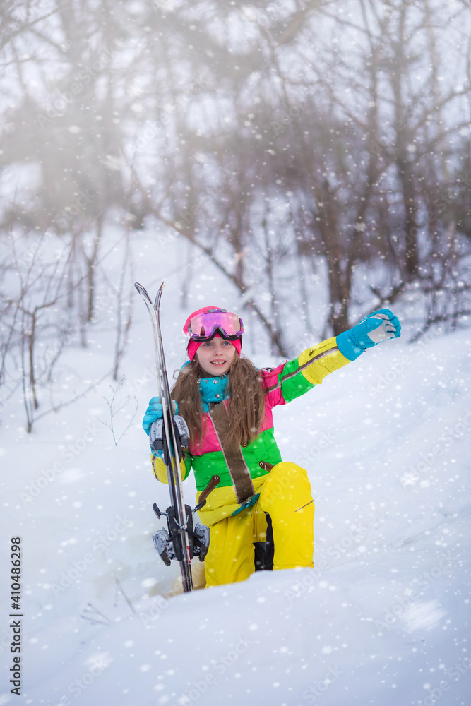 Portrait of a girl skier on a snowy mountain at a ski resort. Active confident caucasian kid girl portrait, goggles and bright suit enjoy winter extreme sport activities.
