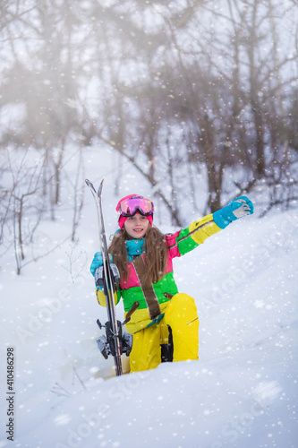 Portrait of a girl skier on a snowy mountain at a ski resort. Active confident caucasian kid girl portrait, goggles and bright suit enjoy winter extreme sport activities.