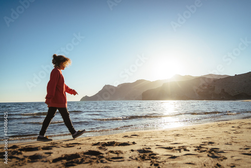 Curly girl walking on the beach in the sunset