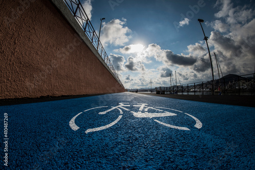 corsia di pista ciclabile di colore azzurro con cielo leggermente nuvoloso