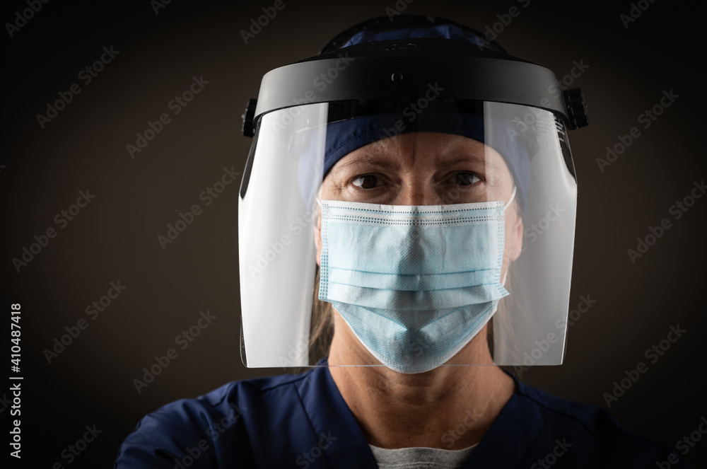 Female Medical Worker Wearing Protective Face Mask and Gear Against Dark Background Female Medical Worker Wearing Protective Face Mask and Gear Against Dark Background