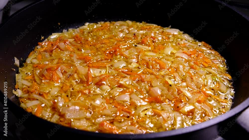 Fry onions and carrots in a pan. Frying with oil. Cooking lunch in the kitchen by the hob. Fry onions and carrots in a pan. Frying with oil. Cooking lunch in the kitchen by the hob.