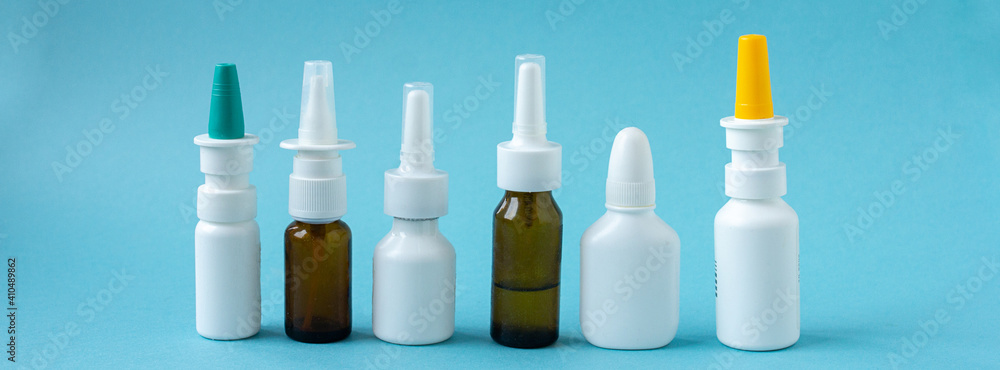 Bottles of nasal spray standing in line on blue background, medicine flat lay, treatment for colds, medical banner Bottles of nasal spray standing in line on blue background, medicine flat lay, treatment for colds, medical banner