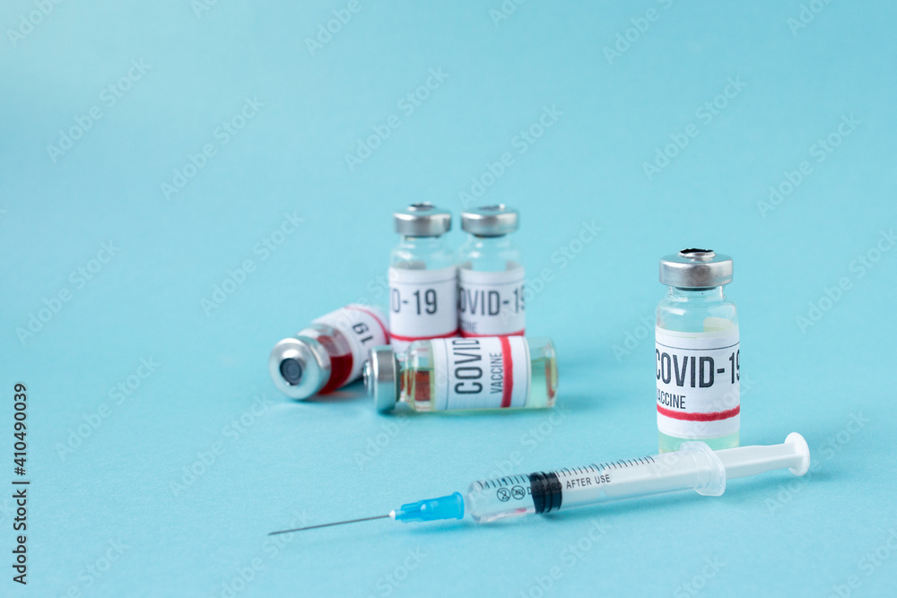 Covid-19 or coronavirus vaccination on blue background, ampoules of vaccine syringe on table, medical banner with copy space Covid-19 or coronavirus vaccination on blue background, ampoules of vaccine syringe on table, medical banner with copy space