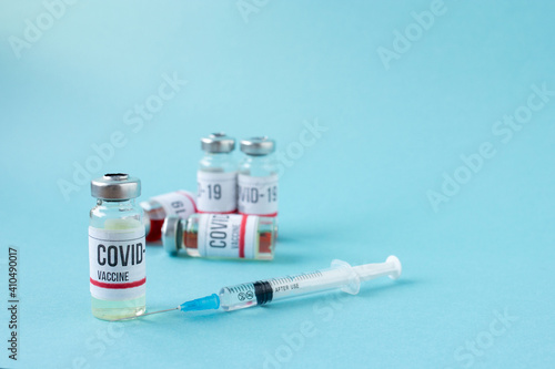 Covid-19 or coronavirus vaccination on blue background, ampoules of vaccine syringe on table, medical banner with copy space