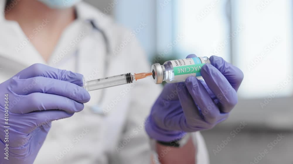 Health and medical concepts. Close-up of doctors hands holding syringe with transparent solution and infusing in ampoul. Process of vaccine development, experimental researches in medical laboratory. Health and medical concepts. Close-up of doctors hands holding syringe with transparent solution and infusing in ampoul. Process of vaccine development, experimental researches in medical laboratory.