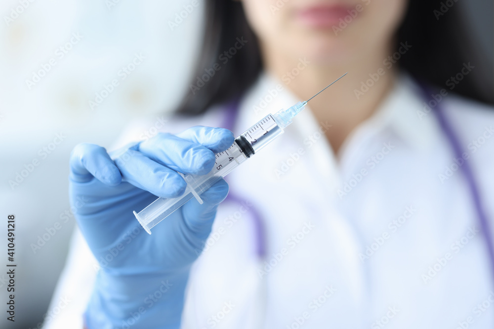 Doctor in rubber gloves holding syringe with medicine closeup Doctor in rubber gloves holding syringe with medicine closeup