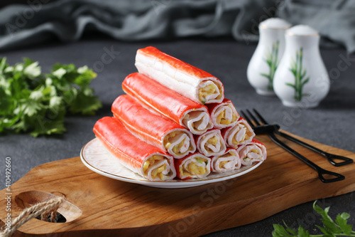Crab sticks stuffed with rice, egg and green onions on a wooden board on a gray background. Closeup