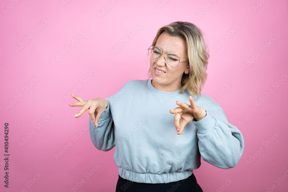 Young caucasian woman wearing sweatshirt over pink background disgusted expression, displeased and fearful doing disgust face because aversion reaction. Annoying concept Young caucasian woman wearing sweatshirt over pink background disgusted expression, displeased and fearful doing disgust face because aversion reaction. Annoying concept