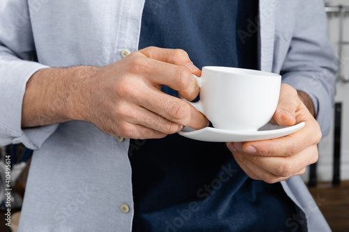 cropped view of man holding cup with coffee and saucer